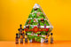 A Christmas-themed hot sauce advent calendar box stands on an orange surface against a bright yellow background, with several small hot sauce bottles arranged in front of it.